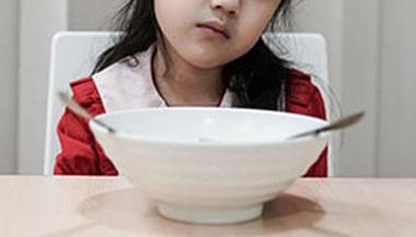 child sits in front of empty bowl