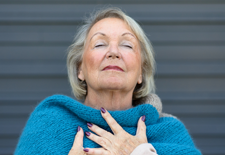 An older woman inhales deeply.