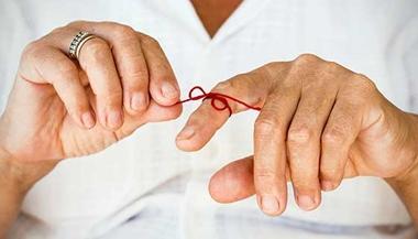 Man with a red string tied around his finger to help remember