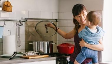 Mother cooking food in the kitchen with her baby