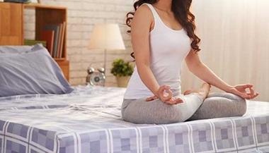 坐在床上做瑜伽姿势的女人
