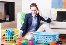woman in work clothes surrounded by laundry basket and children's toys