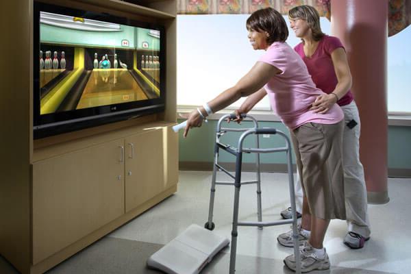 Female stroke rehab patient playing Wii bowling with a rehab therapist