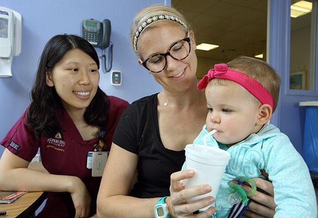 a speech-language pathologist works with a baby and her mother on swallowing