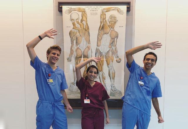 Students pose in front of an anatomical diagram