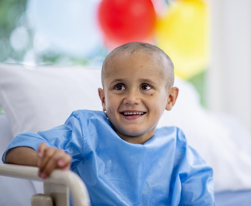 boy with cancer smiling in hospital bed
