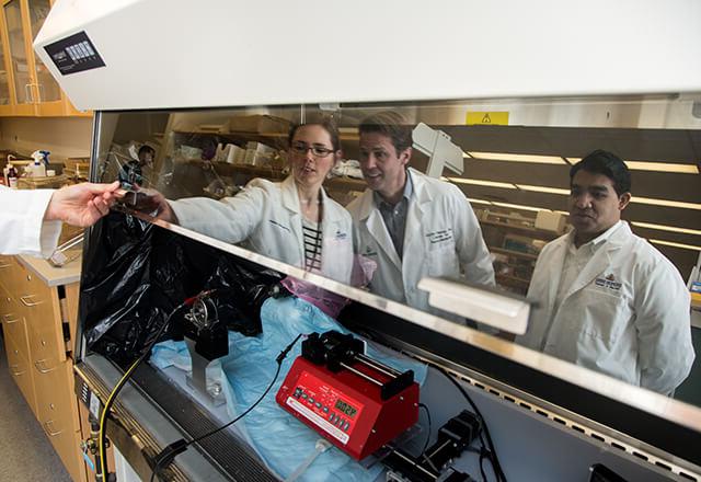 researchers huddle around tool